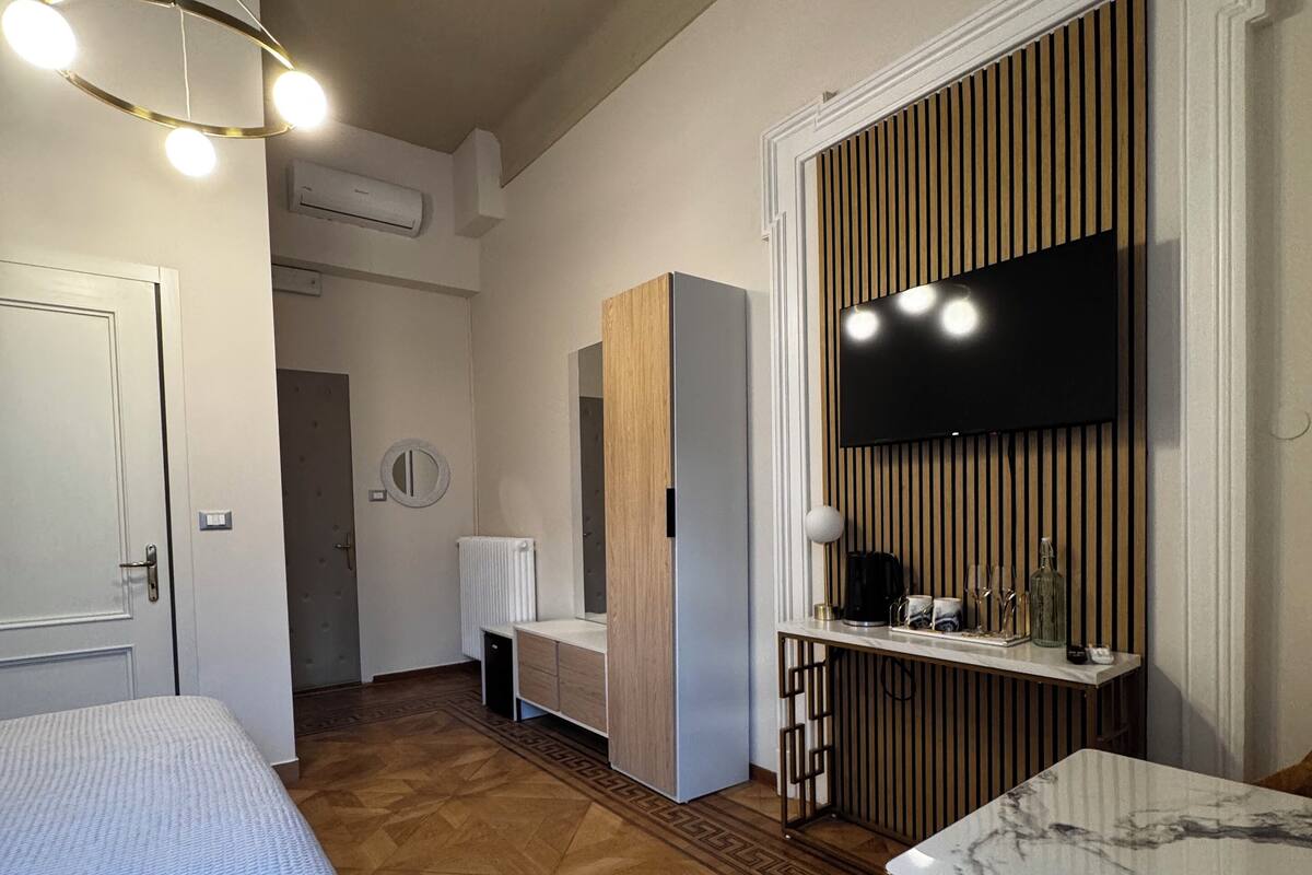 A hotel room with a bed, a desk, a TV, and a minibar.