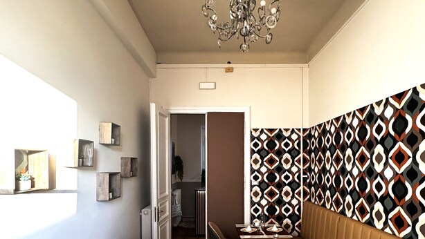A dining area with a herringbone wood floor, a chandelier, and a patterned wall. - Bed & Chic art rooms (Trieste)