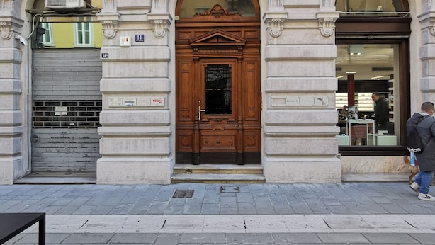 A building with a large wooden door, arched windows, and a stone facade. - Bed & Chic art rooms (Trieste)