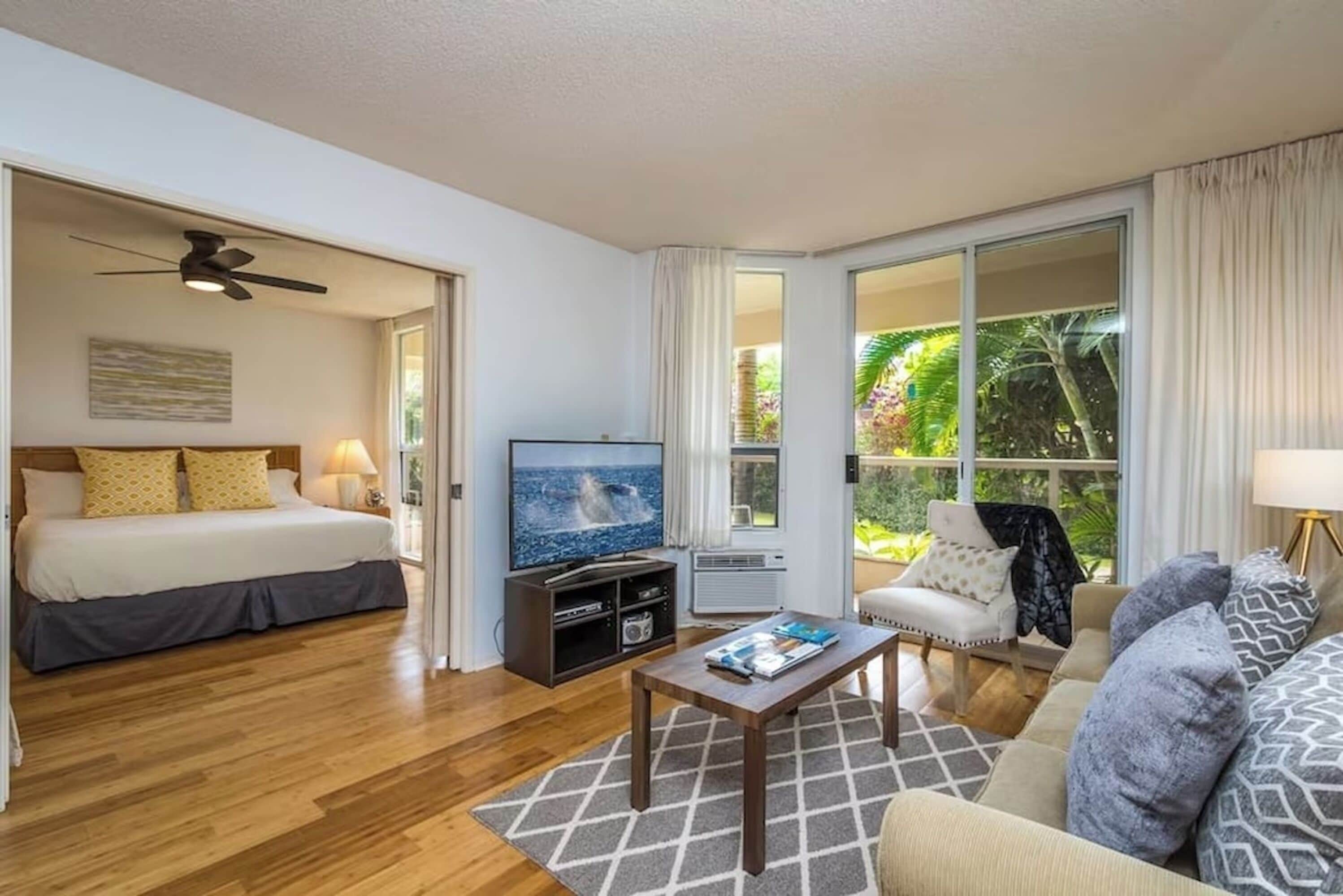 A hotel room with a bed, a TV, a coffee table, and a sofa.