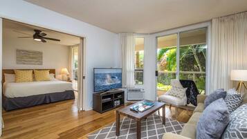 A hotel room with a bed, a TV, a coffee table, and a sofa.