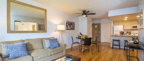 A living room with a sofa, coffee table, and a dining area with chairs and a table.