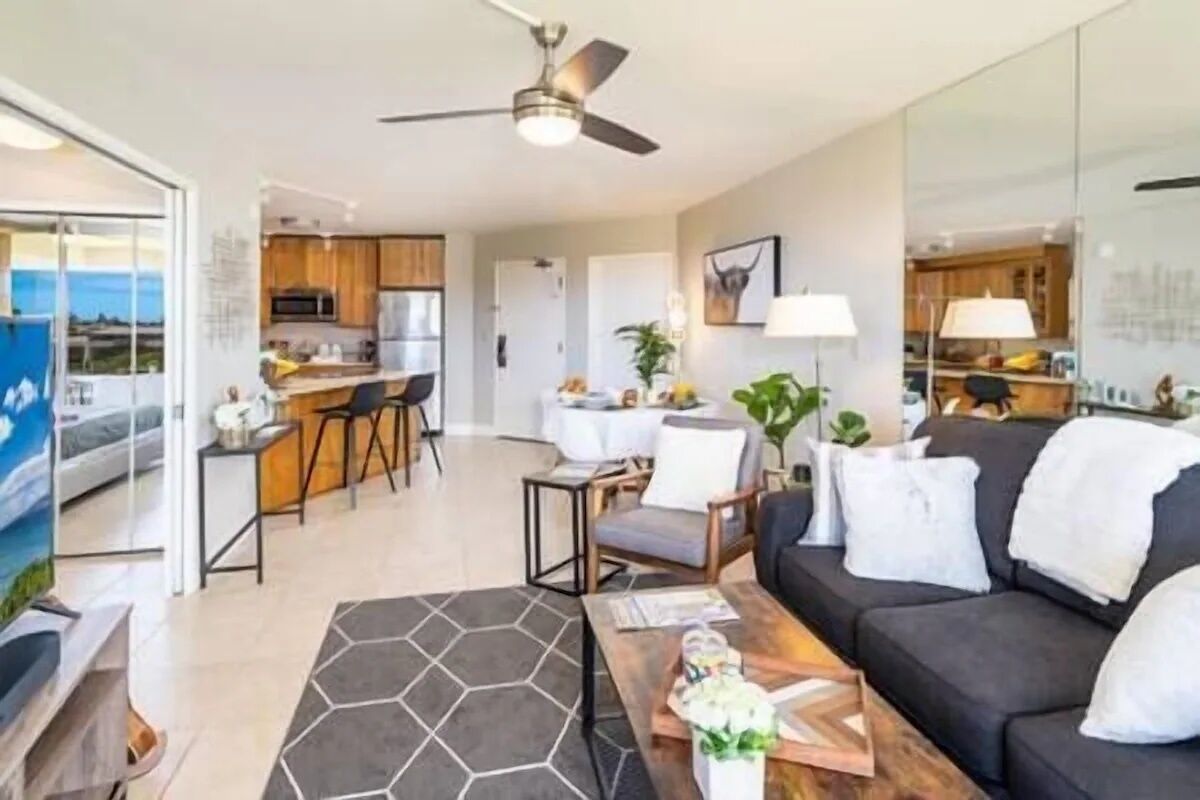 A modern living room with a sofa, coffee table, and a view of the kitchen.