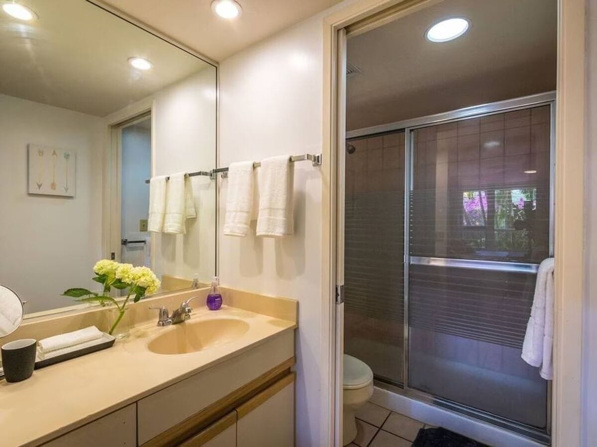 A bathroom with a sink, mirror, and shower.