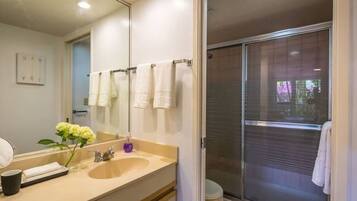 A modern bathroom with a large mirror, a sink, and a shower area.