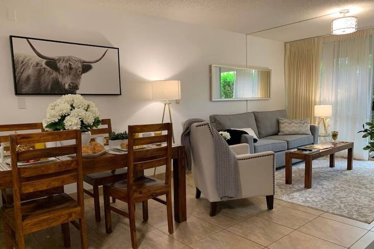 Un salon comprenant un coin repas, un canapé gris, une table basse et une lampe.