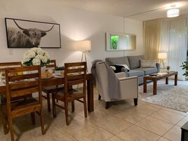 Una sala de estar con comedor, un sofá gris, una mesa de centro y una lámpara.