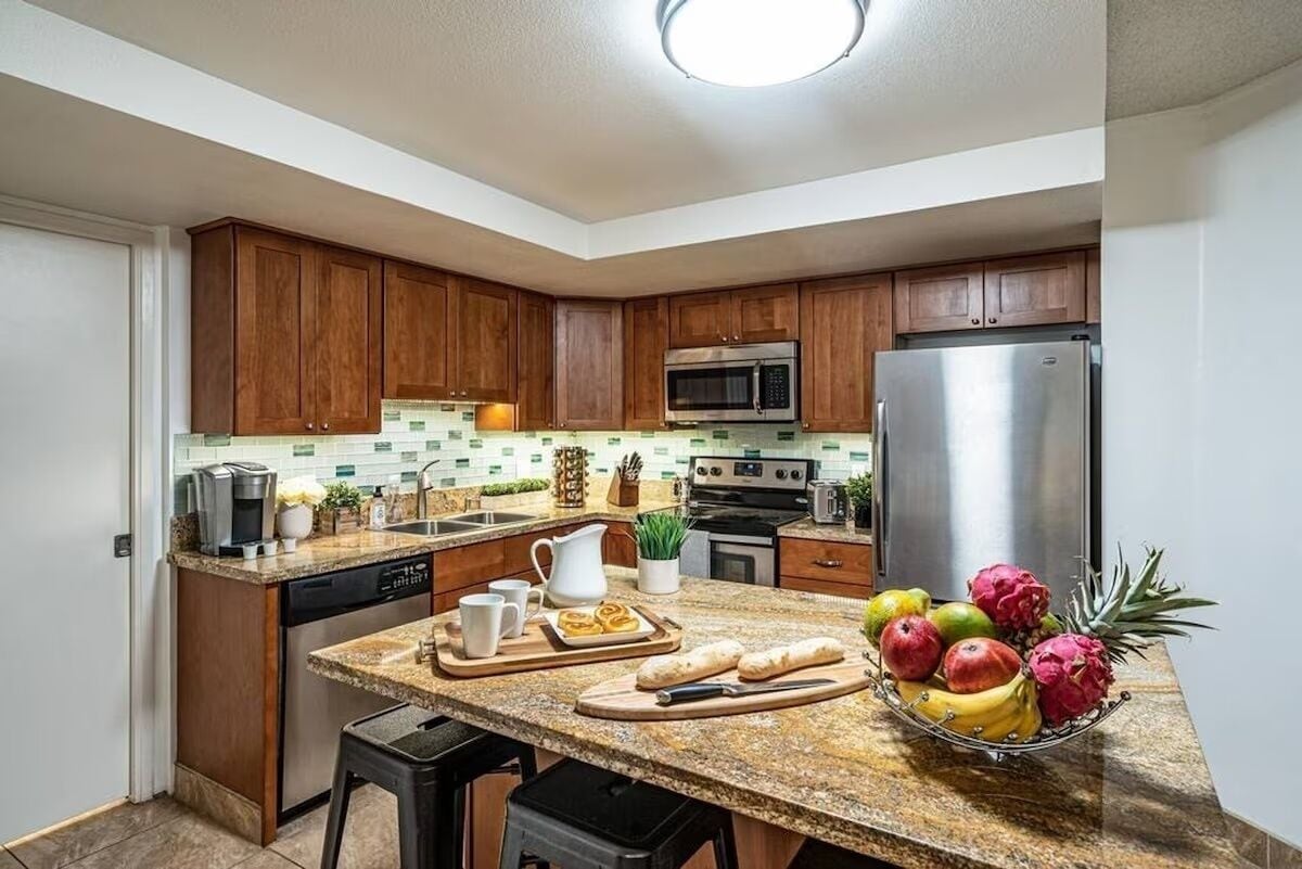 A modern kitchen with wooden cabinets, stainless steel appliances, and a granite countertop.