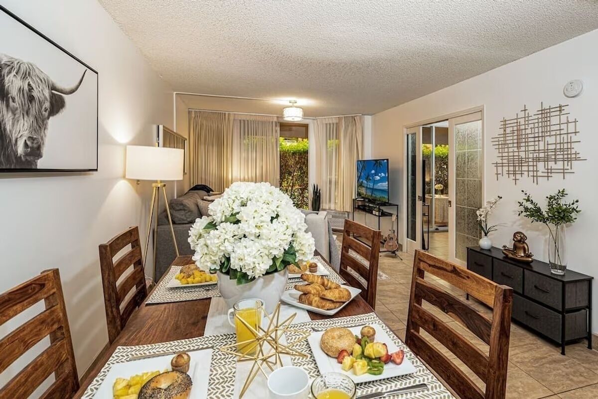 Un comedor con una mesa preparada para el desayuno, que incluye cruasanes, fruta y una taza de café.