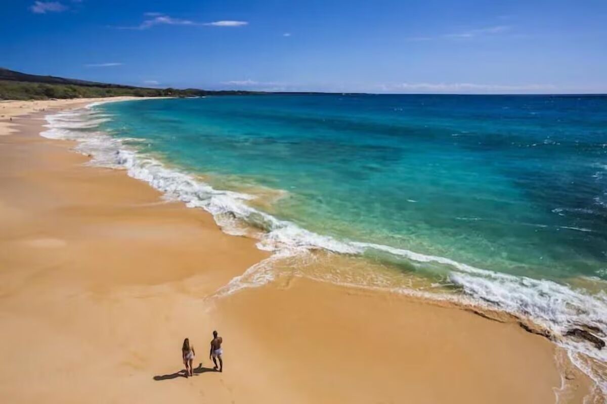 A beach with clear turquoise waters and a sandy shore.