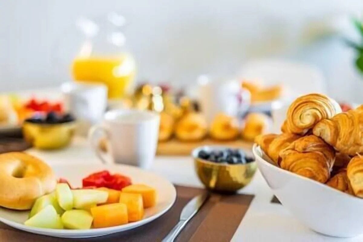 A breakfast setting with croissants, a plate of fruit, and a glass of orange juice.