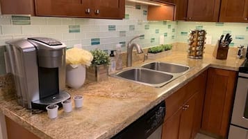 A kitchen with wooden cabinets, a coffee maker, a sink, and a dish rack.