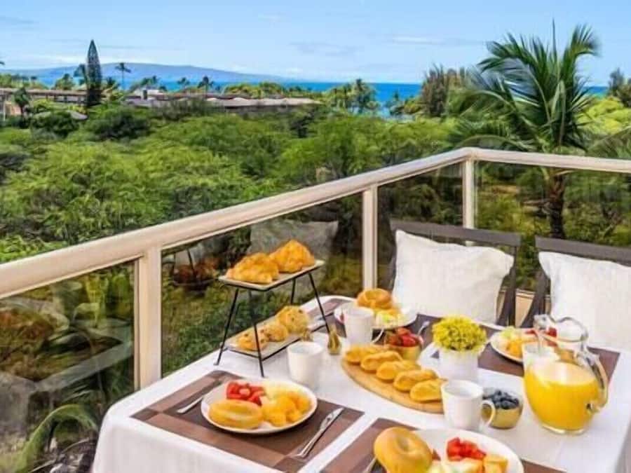 Una mesa de desayuno en un balcón con vistas a un paisaje tropical.