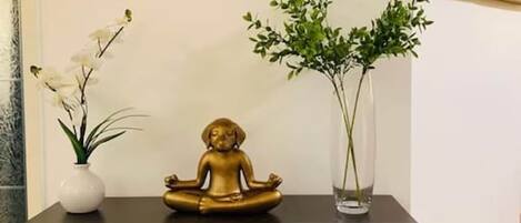 A black console table with a gold statue, two vases with plants, and a wall art piece.