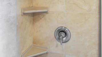 Une douche équipée d’un pommeau de douche à effet pluie et d’un robinet mural.