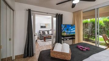 Un dormitorio con cama, televisor, balcón con vistas y ventilador de techo.