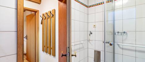 Une salle de bain avec une douche, des murs carrelés, une porte en bois et un porte-serviettes.