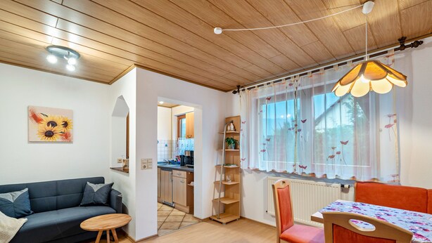 Una sala de estar acogedora con un sofá, una mesa de comedor y una cocina al fondo.