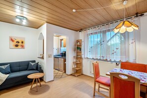 Ett mysigt vardagsrum med en soffa, ett matbord och ett kök i bakgrunden.