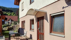 Un edificio de dos pisos con un patio, una mesa y una silla.