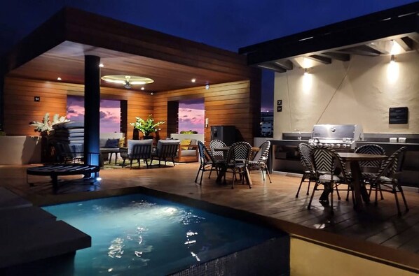 Un patio moderno al aire libre con piscina, zona de estar y barbacoa.