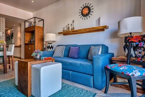 Ein modernes Wohnzimmer mit einem blauen Sofa, einem Holztisch und einem blumigen Sessel.