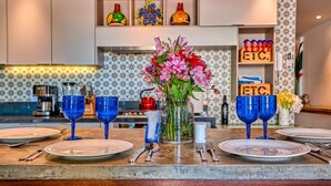 Una encimera de cocina con un jarrón de flores, cristalería azul y una máquina de café.