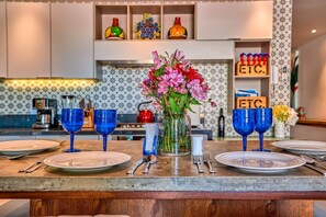 Una encimera de cocina con un florero, cristalería azul y una cafetera.