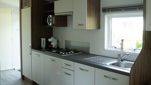 A modern kitchen with a gas stove, a coffee maker, and a window with a view.
