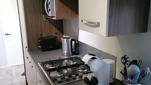 A compact kitchen with a gas stove, a coffee maker, and a toaster. - Vakantiepark de Zeeuwse Parel - Summerlove (Scherpenisse)