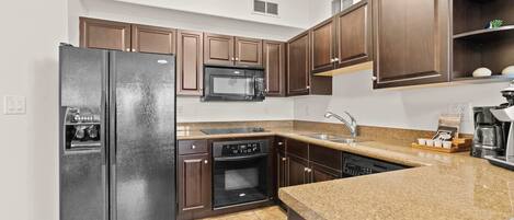 A modern kitchen with a refrigerator, microwave, oven, and dishwasher.