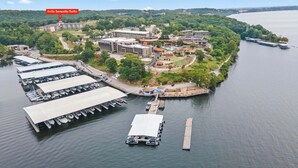 An aerial view of a lakeside hotel with multiple buildings, a marina with boats, and a dock. - Avila Serenity Suites - For 6 (Lake Ozark)