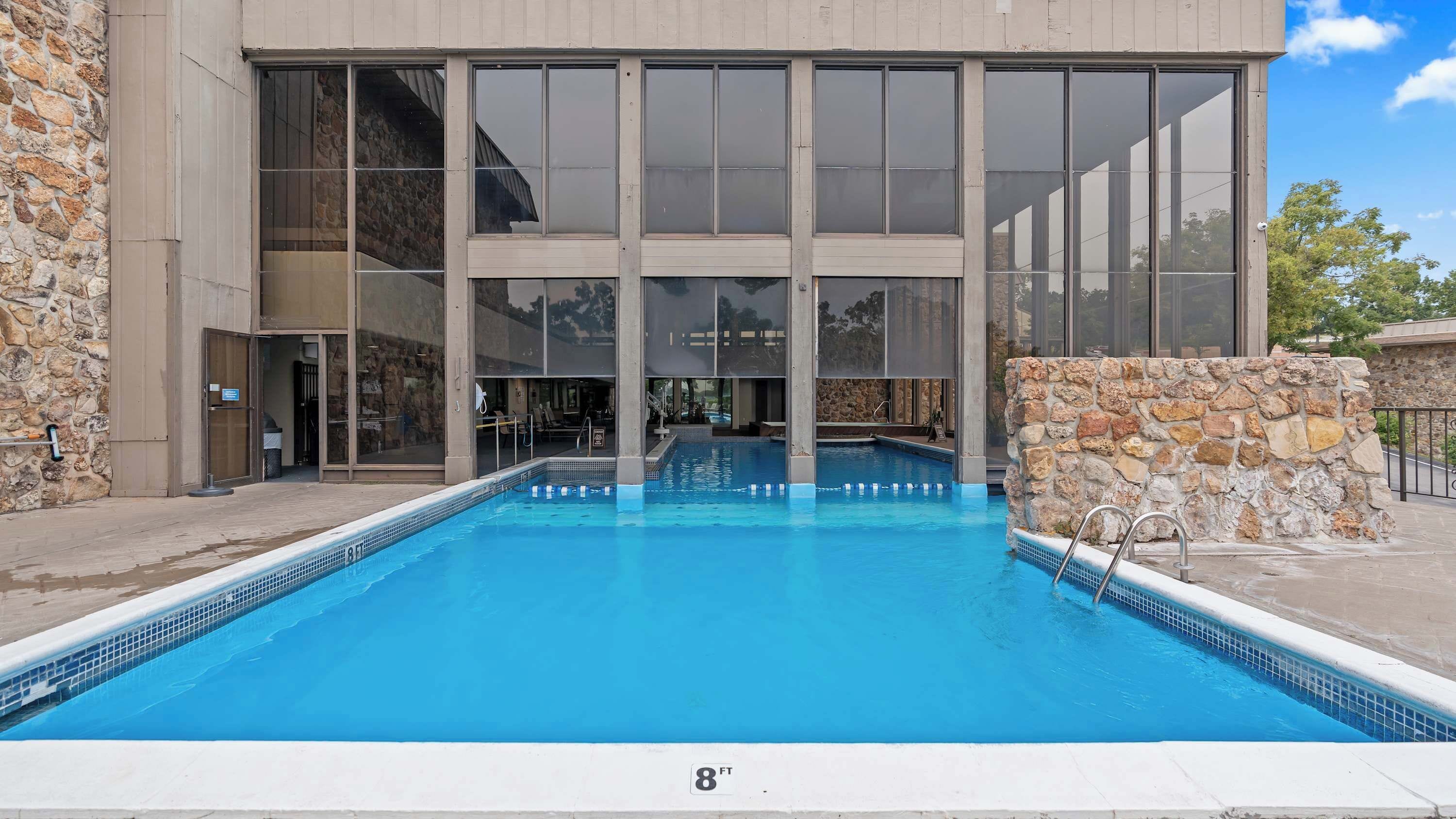 A modern building with a large pool, stone walls, and large windows.