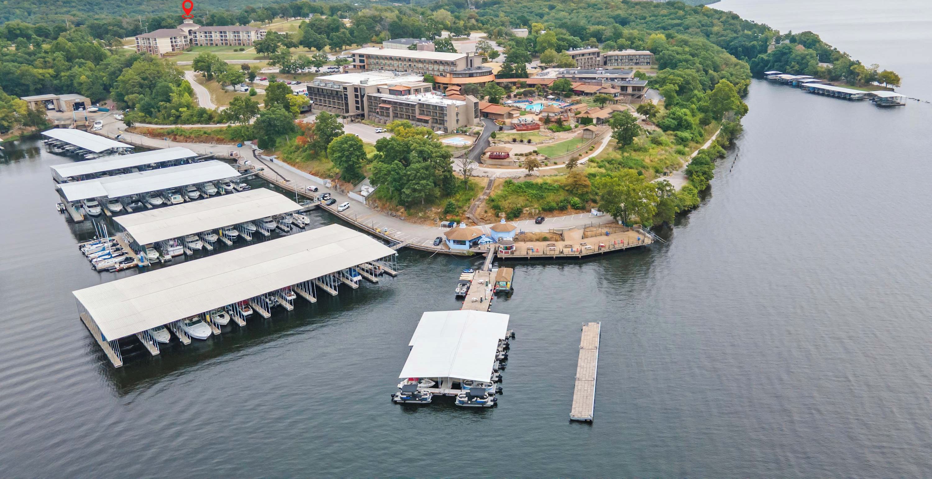 An aerial view of a lakeside hotel with multiple buildings, a marina with boats, and a dock.