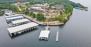 An aerial view of a lakeside hotel with multiple buildings, a marina with boats, and a dock. - Avila Serenity Suites - For 6 (Lake Ozark)