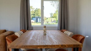 A dining table with six chairs, a vase, and a window with curtains.