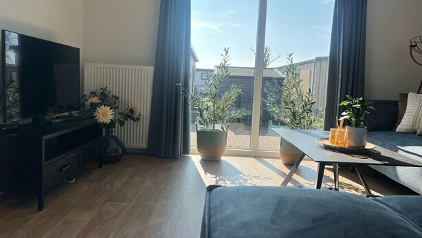 A modern living room with a television, sofa, and dining area.