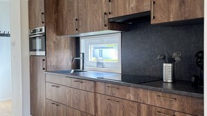 A modern kitchen with wooden cabinets, a stainless steel sink, and a window overlooking a balcony.