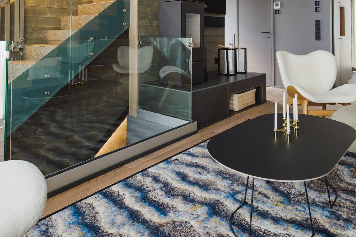 A modern interior with a glass staircase, a black table, and a white chair.