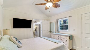 Un dormitorio con cama, cómoda y televisor montado en la pared.