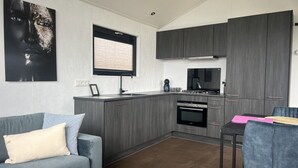 A modern kitchen with grey cabinetry, a built-in oven, and a window with blinds.