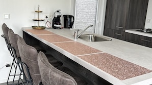 Een keuken met een granieten aanrecht, een roestvrijstalen spoelbak, een koffiezetapparaat en een waterkoker.