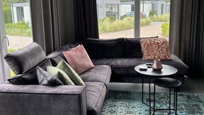 Een moderne woonkamer met een grijze modulaire bank, een ronde salontafel en een klein bijzettafeltje.