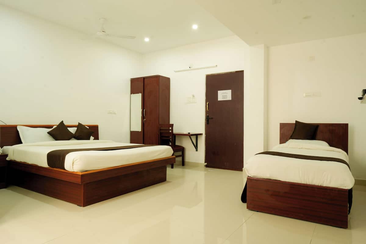 A hotel room with two wooden beds, a desk, a chair, and a wardrobe.