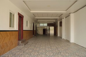 A hallway with patterned flooring, a wooden wall, and a door with a red frame. - JR Service Apartment  (Coimbatore)
