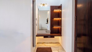 A hallway with a wooden vanity, a mirror, and a marble floor. - JR Service Apartment  (Coimbatore)