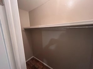 A corner of a room with a white baseboard, a brown wall, and a wooden floor.