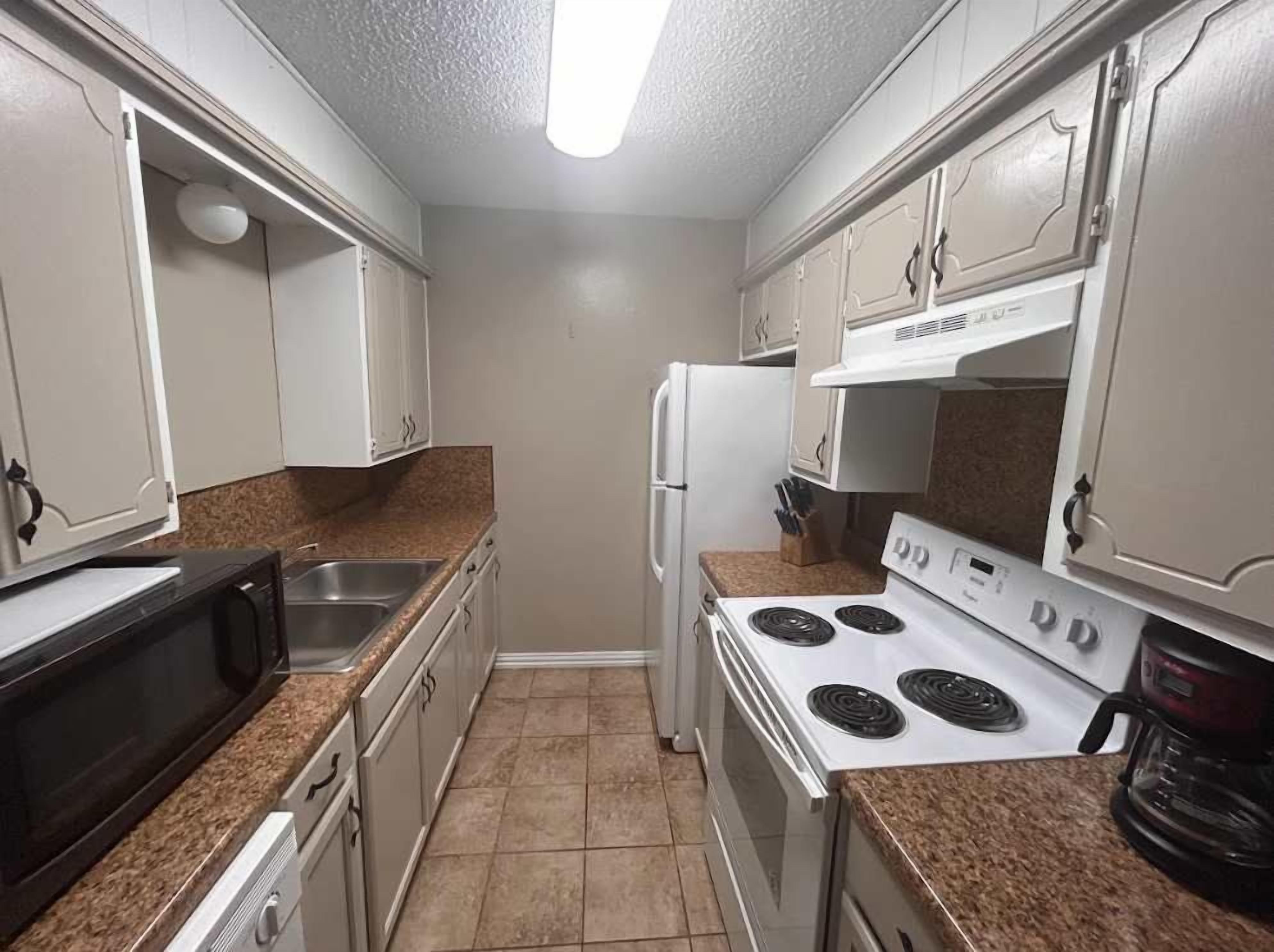 A kitchen with white cabinets, a microwave, a stove, and a refrigerator.