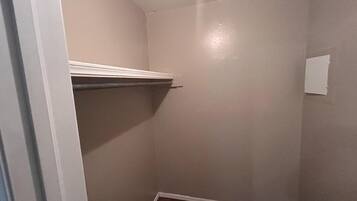 A small, enclosed room with a sloped ceiling, a wooden floor, and a white door.