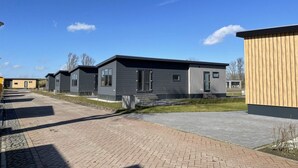 Una hilera de modernas casas móviles de un piso, con amplios ventanales y un paseo pavimentado.